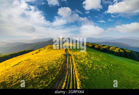 Fantastische Szene auf den Sommerbergen. Grünes Gras, Landstraße und blauer Himmel bei fantastischer Morgensonne. Karpaten, Europa. Landschaftsfotografie Stockfoto