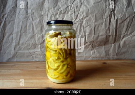 HAYDOCK. ST. HELENS. LANCASHIRE. 10-01-21. Ein Glas mit hausgemachten, konservierten gesalzenen Zitronen, die auf einem Holzbrett vor einem schlichten Hintergrund platziert sind. Stockfoto