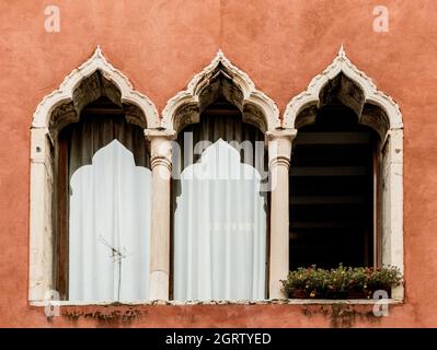 Ein typisches dreibogige Fenster (oder drei-Licht-Fenster) eines Gebäudes, an einer roten Wand, in einer Straße von Venedig, Venetien, Italien, Europa Stockfoto