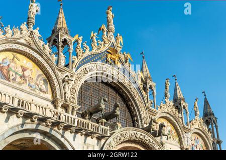 Detail der façade der Markusbasilika auf dem Markusplatz mit Skulpturen und den byzantinischen Bronzestatuen von vier Pferden, Venedig, Italien, E Stockfoto