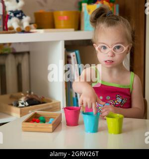 Mädchen mit Down-Syndrom entwickelt feinmotorische Fähigkeiten der Hände Stockfoto