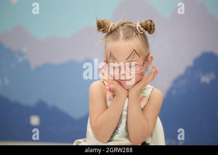 Schönes Mädchen mit Down-Syndrom mit Aqua Make-up für ihren Geburtstag Stockfoto