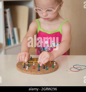 Mädchen mit Down-Syndrom entwickelt feinmotorische Fähigkeiten der Hände Stockfoto