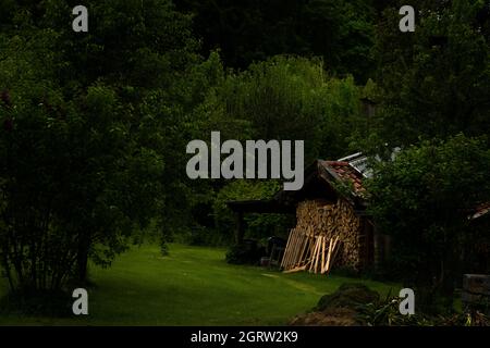 Gemütliche kleine Scheune mit einem Haufen Brennholz in den Alpen verloren. Foto aus Füssen, Bayern, 2019 Stockfoto
