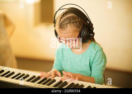 Ein Mädchen mit Down-Syndrom lernt Klavier spielen und hört Musik Stockfoto