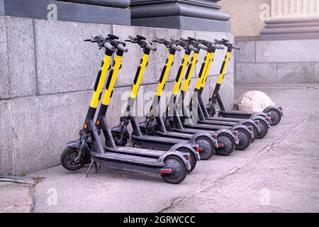 Elektroroller in Reihe auf dem Parkplatz. Verleihsystem auf den Straßen der Stadt. Moderne Elektroroller Parkplatz. Alternativer Transport, erneuerbar Stockfoto