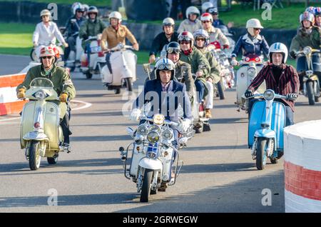 Quadrophenia-Star Phil Daniels eröffnete das Goodwood Revival 2014, indem er eine Gruppe von „Mods“ auf der Rennstrecke führte und einen Motorroller im Retro-Look fuhr Stockfoto