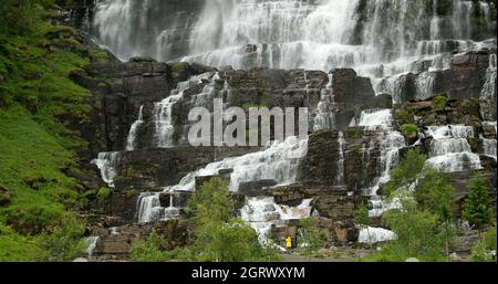 Voss, Hordaland, Norwegen. Wasserfall Tvindefossen Im Frühling. Junge Kaukasische Frau Dame Tourist Traveler Walking Besuch Höchsten Wasserfall Von Norwegen Stockfoto