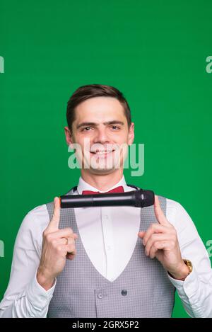 Der Entertainer. Junger eleganter sprechender Mann mit Mikrofon, isoliert in einem Studio. Stockfoto