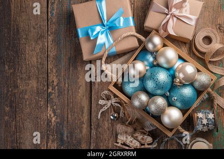 Weihnachtskomposition mit Weihnachtskugeln und Geschenkboxen auf Holzhintergrund. Draufsicht, Kopierbereich. Stockfoto