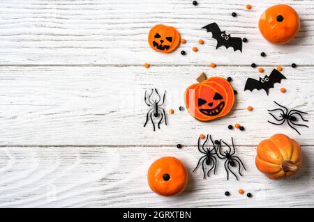 Halloween Hintergrund mit Cookies, Spinnen und Fledermäuse, Draufsicht. Halloween lustige Objekte auf weißem Holztisch, flach liegend. Traditionelles Hallowen Essen und Stockfoto