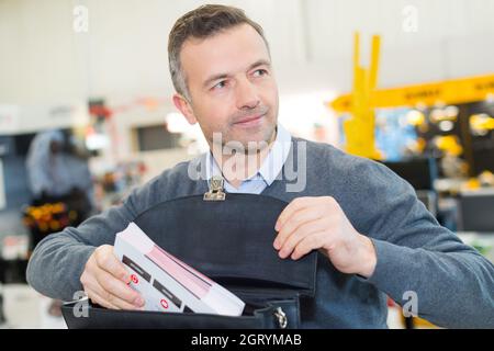 Geschäftsmann, der weißes Papier in ein blaues Aktendokument einlegt Stockfoto