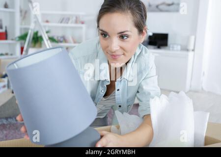 Frau Auspacken Lampe aus Karton in ihrem neuen Zuhause Stockfoto