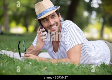 Der Mann, der einen Anruf macht, liegt auf dem Gras Stockfoto