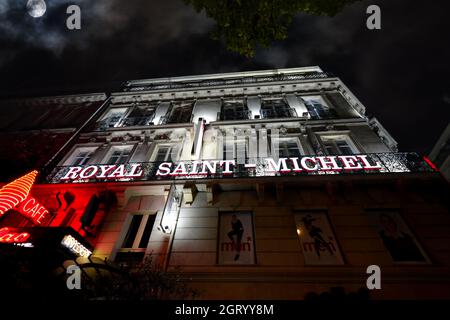 Abendlicher Blick auf die beleuchteten roten und weißen Neonschilder und die Fassade des Hotel Royal Saint-Michel bei Nacht im Quartier Latin von Paris, Frankreich. Stockfoto