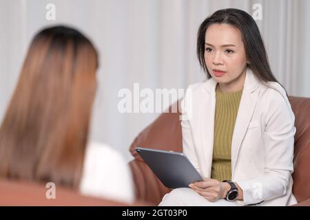 Eine südostasiatische Psychologin berät sich in einer Psychotherapiesitzung mit einer Frau Stockfoto