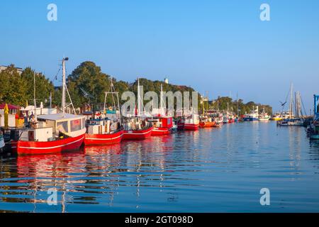 Eine Reihe von roten Touristen- und Fischerbooten säumen den Alten Strom Kanal im Küstenort Warnemunde an der Ostsee. Stockfoto