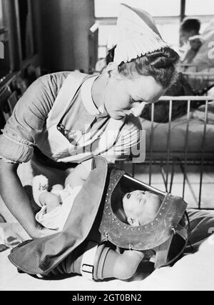 Eine Krankenschwester platziert ein weinendes Baby während einer Übung in einem Londoner Krankenhaus im Jahr 1940 in sein Gas-Atemschutzgerät. Stockfoto