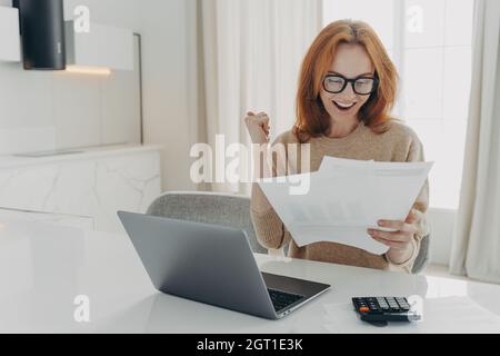 Freiberuflerin prüft Berechnungen mit der Faust und schaut sich gerne Papierdokumente an Stockfoto