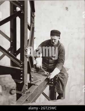 EMPIRE STATE BUILDING NY, NY 1930 - 1931. Allgemeine und detaillierte Ansichten des im Bau befindlichen Empire State Building, in denen Arbeiter verschiedene Aufgaben wie das Positionieren, Schweißen und Nieten von Stahl, das Heben von Materialien und Hilfsgütern sowie das Betreiben und Reparieren von Maschinen zeigen. Es gibt auch eine Vogelperspektive auf Midtown Manhattan, die andere Gebäude zeigt, die im Bau sind. Fotografien von: Hine, Lewis Wickes, 1874-1940 . Stockfoto