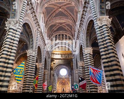 Siena, Italien - August 15 2021: Innenansicht des Doms von Siena und Hauptschiff mit Contrada-Flaggen Stockfoto