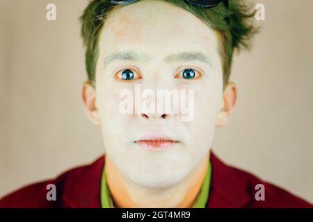 Schauspieler mit weißem Make-up im Gesicht und grünem Haar. Schmiernase von Clown oder Pantomime. Person im Anzug schaut auf die Kamera. Theaterkonzept. Stockfoto