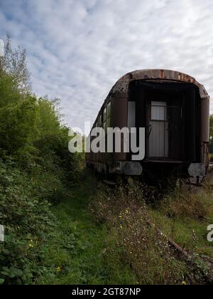 Alter Eisenbahnwagen, der auf einer alten, mit Unkraut überwucherte Eisenbahn verlassen wurde Stockfoto