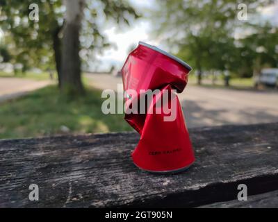 Zerknitterte Sodadose mit der Aufschrift „Zero Calories“ (rumänisch: Zero Calorii) auf einer Bank auf einem Parkplatz am Straßenrand. Stockfoto