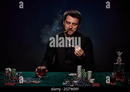 Bärtiger Casino Spieler Mann, der Poker auf dem grünen Tisch spielt Stockfoto