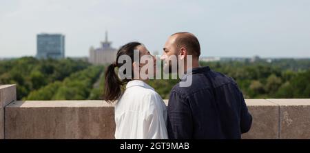 Liebhaber glücklich Paar küssen auf Turm Dach Feier Beziehung Jubiläum stehen am Beobachtungspunkt genießen schöne Aussicht auf die Metropole. Landschaft mit städtischen Gebäuden Stockfoto