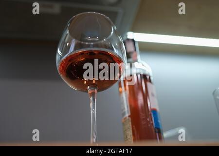 Glas mit gegossenem Alkohol und Flasche befindet sich in der Nähe auf dem Tisch Stockfoto