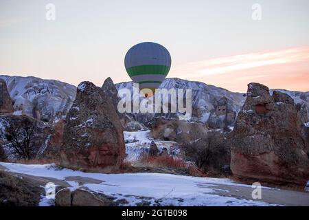 Heißluftballons fliegen über spektakuläre Kappadokien. Wunderschöne Aussicht auf Heißluftballons, die im Sonnenaufgangslicht über der Berglandschaft schweben Stockfoto