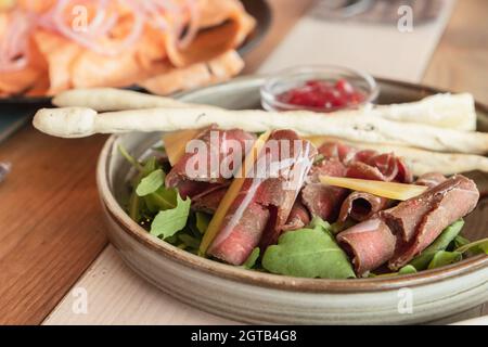 Stroganina auf einem Teller. Es handelt sich um ein Gericht der Ureinwohner des nördlichen arktischen Sibiriens, das aus rohem, dünnem, in Scheiben geschnittenem gefrorenem Fisch oder Rindfleisch besteht Stockfoto