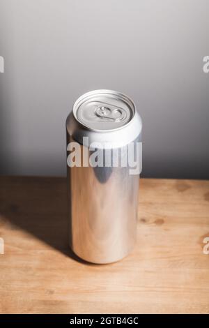Voll geschlossene, glänzende Aluminiumkiste steht auf einem Holztisch, Standard-Softdrink-Verpackung, vertikales Foto Stockfoto