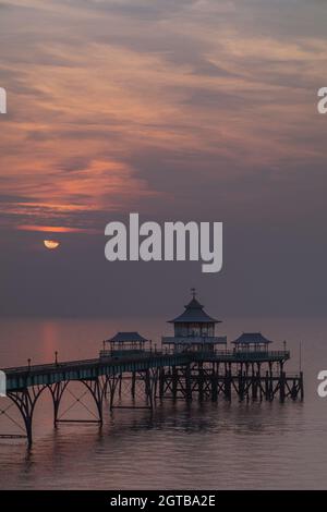 Clevedon Pier bei Sonnenuntergang mit der Sonne über dem Horizont zu untergehen Stockfoto