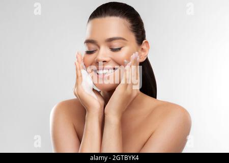 Happy girl mit perfekt glühende Haut Anwendung schäumende Reinigungsmittel für die Hautpflege und feuchtigkeitsspendende zu Hause Stockfoto