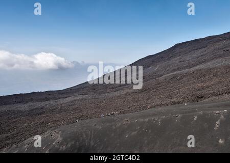 Eine Gruppe von Touristen auf einer geführten Wanderung hoch auf der östlichen Seite des Ätna, Sizilien, Italien Stockfoto