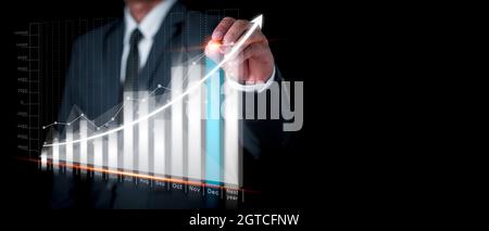 Geschäftsmann zeichnet ein Diagramm für den zukünftigen Wachstumsplan des Unternehmens. Geschäftsentwicklung zum Erfolg. Finanzdiagramme mit neuen modernen Comp Stockfoto