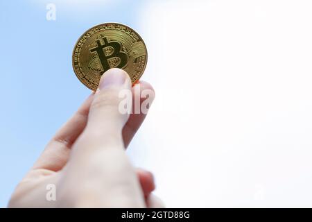 Hand hält ein goldenes Bitcoin-Münzsymbol, klaren Himmel Hintergrund, kopieren Raum. BTC-Münze, Kryptowährung persönliche Finanzen, Krypto Währung Aktien Marke Stockfoto