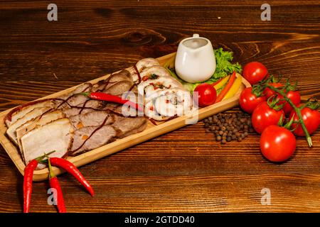 Fleischsortiment in Holztablett mit Chili und Kirschtomaten dekoriert. Das Essen im Restaurant war ganz in der Nähe Stockfoto