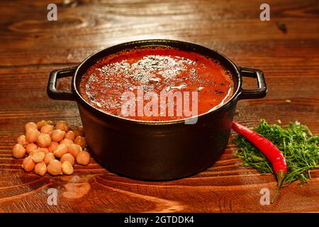 Leckere Tomatensuppe in einer Metallschüssel, serviert im armenischen Restaurant, das mit marinierten Kichererbsen und Chili dekoriert ist. Das Essen im Restaurant war ganz in der Nähe Stockfoto