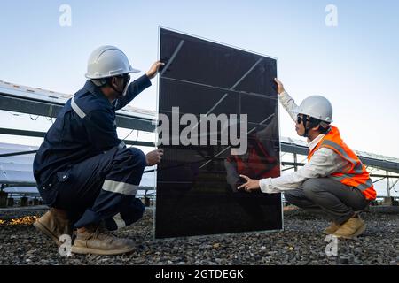 Techniker hebt die Solarzelle, um die beschädigte zu ersetzen, Alternative Energie, um die Energie der Welt zu sparen, Photovoltaikmodul Idee für sauber Stockfoto