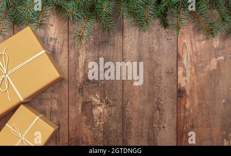 Weihnachtskomposition. Weihnachtsgeschenk, Tannenzweige auf rustikalem Holzhintergrund. Schöne Geschenke und Tanne. cristmas Elemente auf dem Tisch. Draufsicht, Kopie SPAC Stockfoto