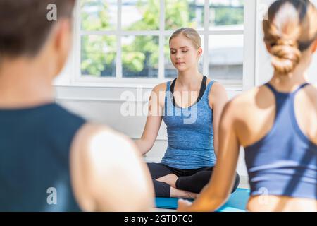 Gruppe von Diversity Yoga Sport Menschen üben mit ihrem Coaching in Yoga-Klasse, junge kaukasische Frau Vermittlung von Yoga mit ihrer Diversity Menschen gro Stockfoto