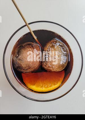Zwei Eiswürfel und eine orangefarbene Scheibe in einem Getränk, die ein lächelndes Gesicht symbolisiert. Glück, Carpe diem, genießen Sie das Good Times Konzept Stockfoto