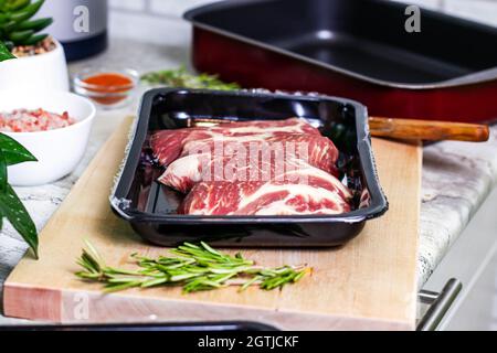 Rohe marmorierte Rindersteak-Scheiben in der Packung auf Holz Schneidebrett Hintergrund bereit zum Kochen. Die Zubereitung eines frischen Fleisches zum Abendessen. Stockfoto