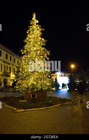 Weihnachten ist da, festlich geschmückter italienischer Platz mit einem herrlichen Weihnachtsbaum in der Mitte mit roten und goldenen Kugeln und viel Sekt Stockfoto