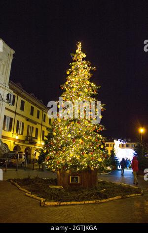 Weihnachten ist da, festlich geschmückter Platz mit einem herrlichen Weihnachtsbaum in der Mitte mit roten und goldenen Kugeln und vielen funkelnden Lichtern Stockfoto