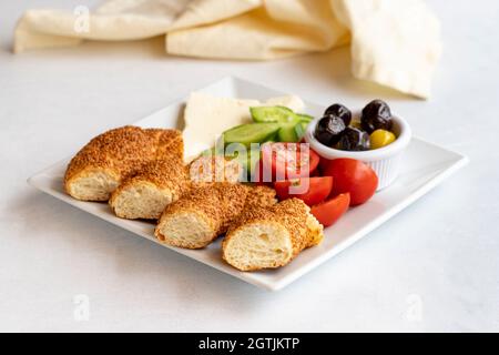 Frühstücksteller auf weißem Hintergrund. Bagels, Fetakäse, Oliven, Tomaten und Gurken. Stockfoto