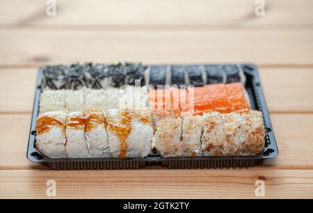 Sushi und Brötchen zu Hause zubereiten. Sushi mit Meeresfrüchten, Salat und weißem Reis. Essen für Familie und Freunde. Eine Reihe verschiedener Brötchen und Sushi auf einem Tablett Stockfoto